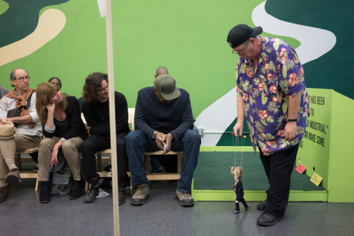 Larry Swanson performs at Los Angeles Poverty Department's "The Back 9" exhibition at the Skid Row History Museum and Archive, 2017. Photo by Linus Shetu © Los Angeles Poverty Department.